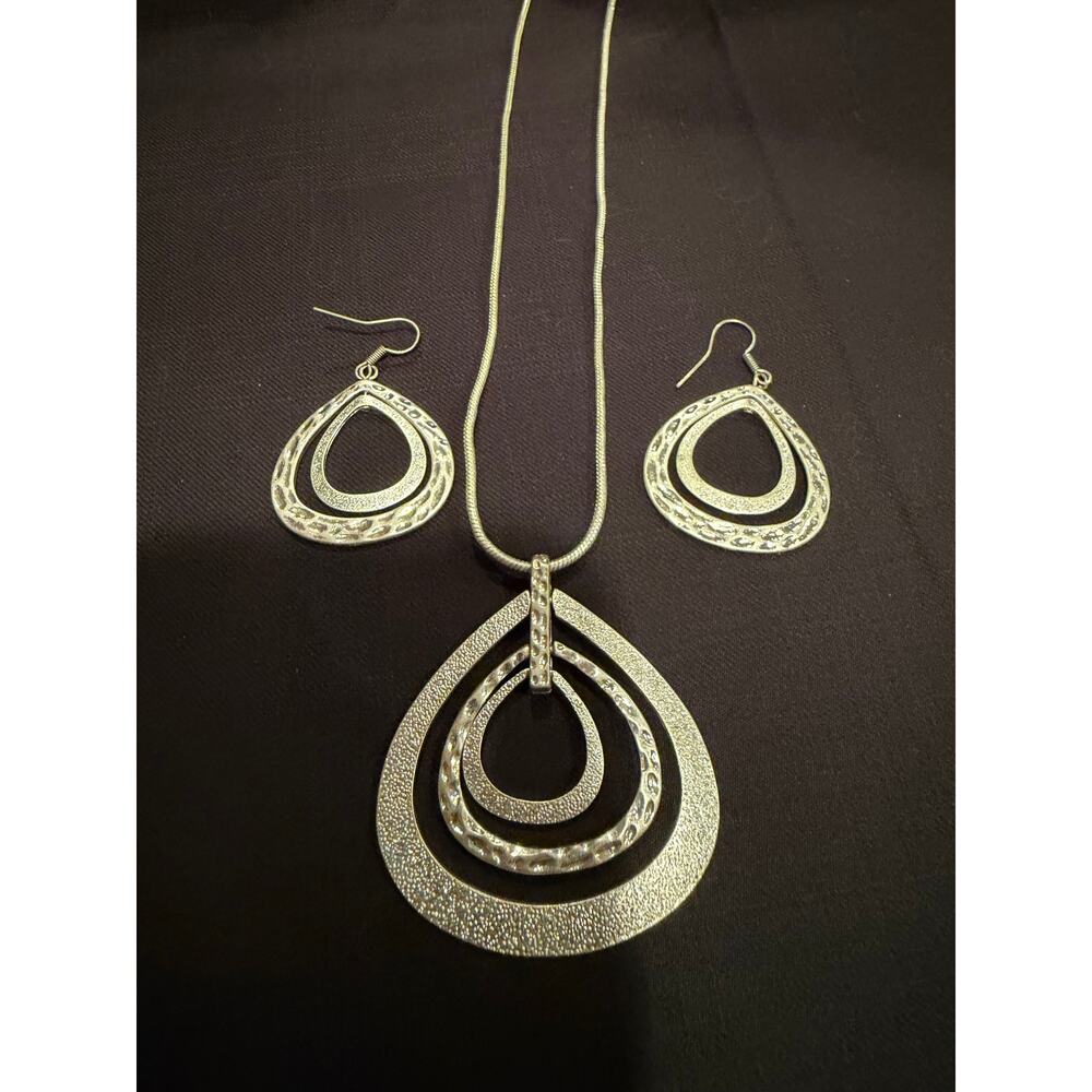 Long artisan-style necklace that features a tiered pendant and matching earrings